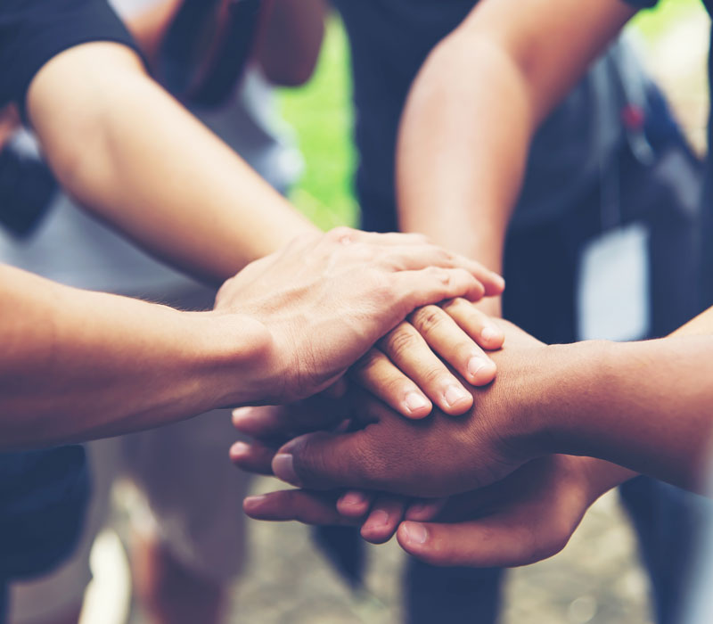 People unite hands together to signify community and teamwork.