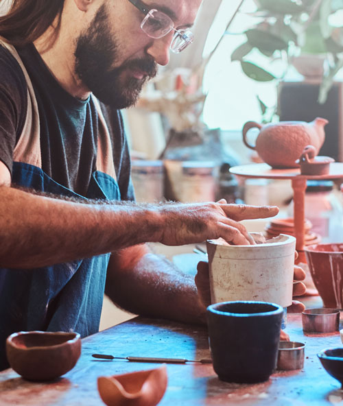 Man diligently making pottery, a form of art.