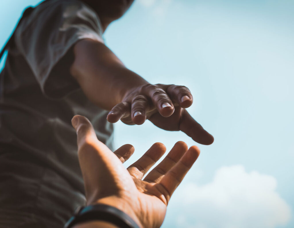 hands of two people reaching out to help each other